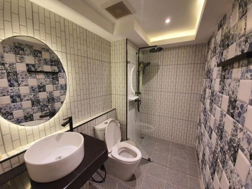 La salle de bains est pourvue d'un lavabo, de toilettes et d'un miroir. dans l'établissement Platinum hotel, à Rayong