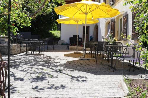 a patio area with umbrellas and a bench at Hotel du Cheval Blanc in Nods