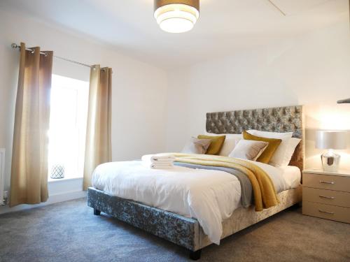 The Gill Gardens Penthouse, Ulverston - Lake District في أولفيرستون: غرفة نوم بسرير كبير ونافذة