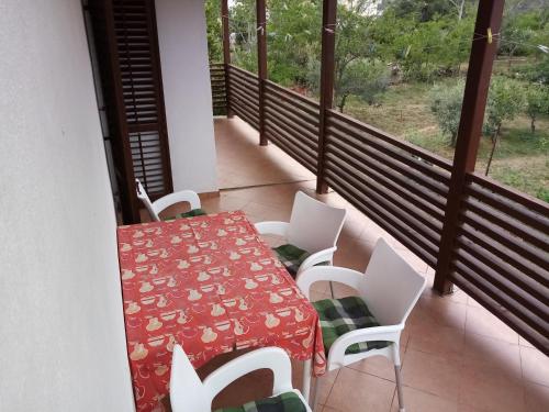 a balcony with a red table and white chairs at Apartments Božito in Nin