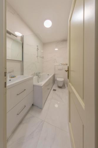 a white bathroom with a tub sink and a toilet at Krka Waterfalls in Skradin