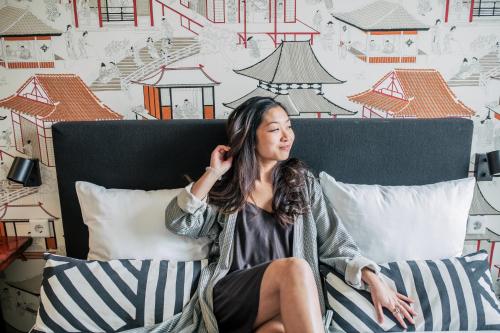 a woman sitting on a bed talking on a cell phone at Pink Flamingo Boutique Hostel in The Hague