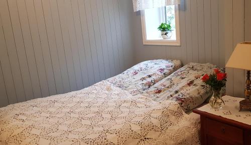 a bed with a comforter and a vase of flowers on a table at Irenegarden - Panorama apartment in Lauvstad