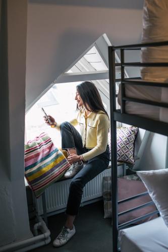 a woman sitting on a bunk bed talking on a cell phone at Pink Flamingo Boutique Hostel in The Hague