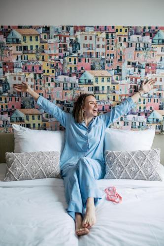a woman laying on a bed with her arms in the air at Pink Flamingo Boutique Hostel in The Hague