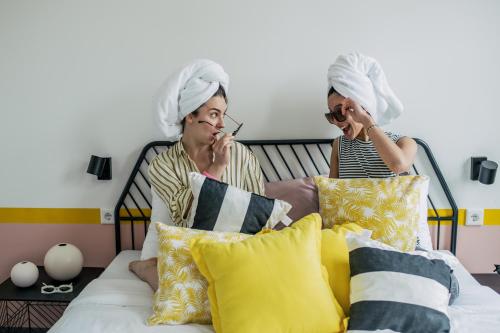 two women sitting on a bed talking on cell phones at Pink Flamingo Boutique Hostel in The Hague