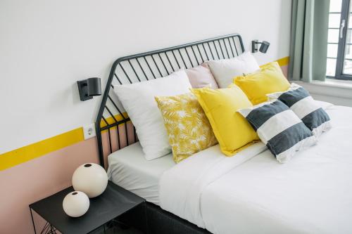 a bed with yellow and white pillows and a table at Pink Flamingo Boutique Hostel in The Hague