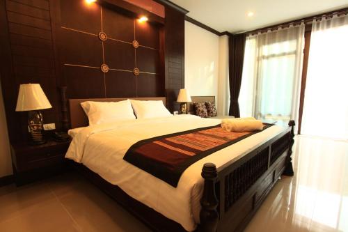 a bedroom with a large bed with a wooden headboard at Baan Ratchiangsaen in Chiang Mai