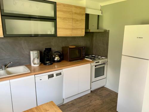 une cuisine avec des armoires blanches et un réfrigérateur blanc dans l'établissement Neige & Soleil Les Rousses, aux Rousses