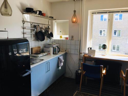 eine Küche mit einem Kühlschrank, einer Spüle und einem Tisch in der Unterkunft Nice room in apartment in Amager in Kopenhagen