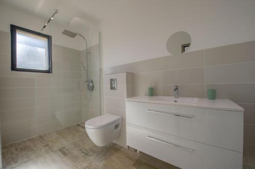 une salle de bain blanche avec des toilettes et un lavabo dans l'établissement Maison Del Onda, à Lecci