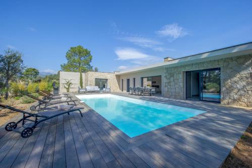 une cour arrière avec une piscine et une terrasse en bois dans l'établissement Maison Del Onda, à Lecci