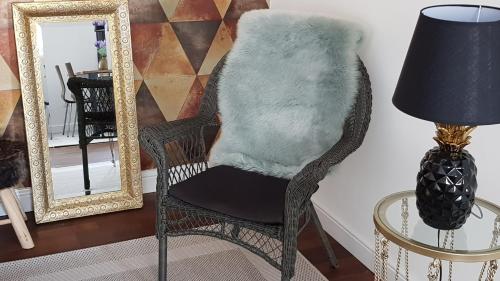 a wicker chair with a faux fur pillow on it next to a mirror at Boutique apartman I in Eger