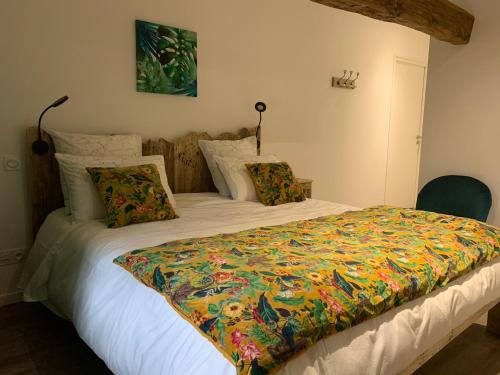 a bedroom with a bed with a colorful blanket on it at Chambres d'hôtes Logis Charrier Le Petit Bignon in Les Épesses