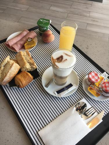 a tray with a cup of coffee and breakfast foods at Novotel Lille Aéroport in Lesquin