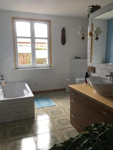 Villa Irene am Inselsee في Mühl Rosin: حمام به مغسلتين وحوض استحمام ونافذة