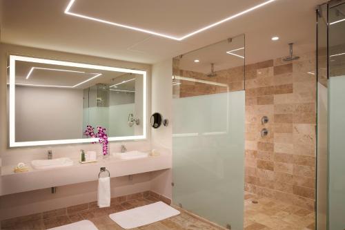 a bathroom with a shower and a sink and a mirror at Dreams Sapphire Resort & Spa in Puerto Morelos