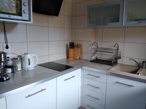 La cuisine est équipée de placards blancs, d'un évier et d'un four micro-ondes. dans l'établissement Apartament Przytulny, à Karwia
