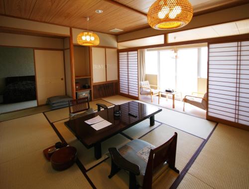 salon z drewnianym stołem i krzesłami w obiekcie Kohan No Yado Yoshidaya w mieście Sado