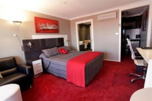a bedroom with a bed and a chair and a desk at Cattlemans Country Motor Inn & Serviced Apartments in Dubbo
