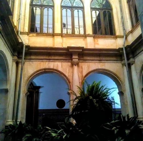 a building with arched windows and a plant in front of it at Hotel Ordóñez Sandoval in Úbeda