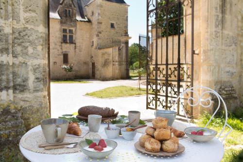 een tafel met borden eten voor een kasteel bij Château de Bois Charmant in Les Nouillers