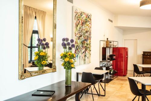 a dining room with a table with flowers in a vase at Hotel Kasteel Solhof in Aartselaar