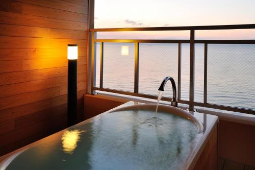 a bathroom with a tub with a view of the ocean at Ibusuki Seaside Hotel in Ibusuki