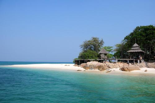 a beach with a resort and the ocean at Koh Munnork Private Island in Ko Munnork
