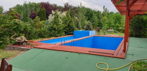 a swimming pool with a wooden deck and a swimming poolvisor at Dobó Tanya in Röszke