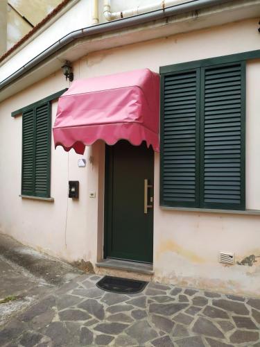 a building with a green door and a pink awning at Accogliente appartamento Fucecchio in Fucecchio