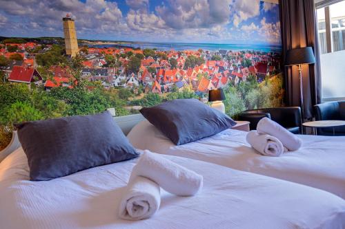 two beds with towels on them in front of a window at `t Wapen van Terschelling in Midsland