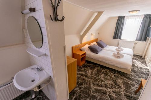 ein kleines Bad mit einem Bett und einem Waschbecken in der Unterkunft `t Wapen van Terschelling in Midsland