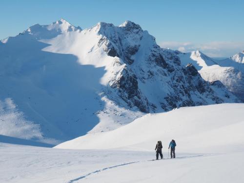 two people skiing on a snow covered mountain at FURU Hostel & Café in Bøstad