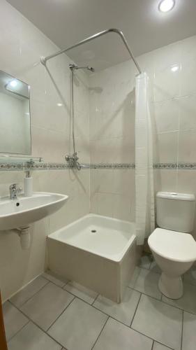 Ein weißes Badezimmer mit Badewanne, Toilette und Waschbecken in der Unterkunft Dana Guest House in Roja