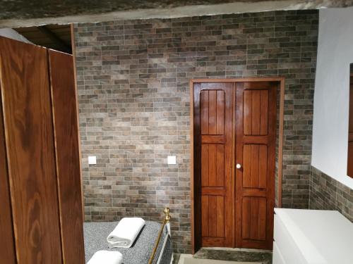 a bathroom with a brick wall and a wooden door at Sossego da Carminho in Monsaraz