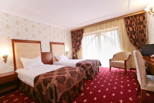 a hotel room with two beds and a desk at Hotel La Castel Iasi in Iaşi