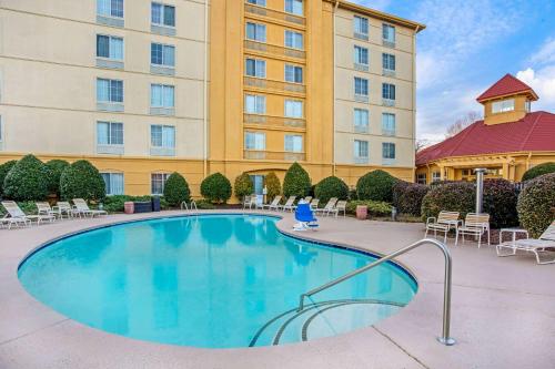 una piscina en un hotel con sillas y un edificio en La Quinta by Wyndham Winston-Salem, en Winston-Salem