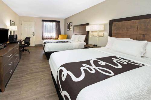 una camera d'albergo con due letti e una televisione di La Quinta Inn by Wyndham West Palm Beach - Florida Turnpike a West Palm Beach