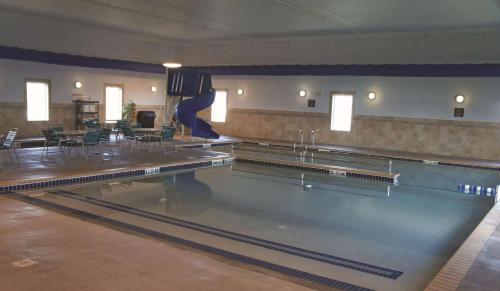 a swimming pool in a gym with chairs and tables at La Quinta by Wyndham Bismarck in Bismarck