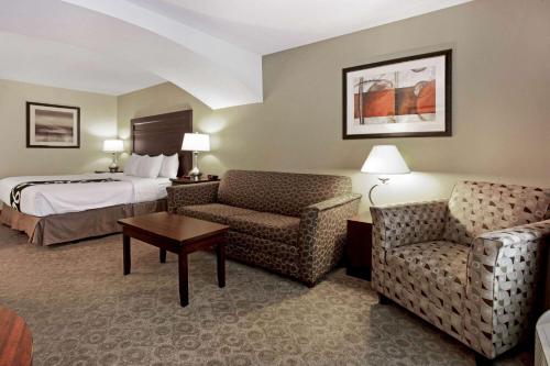 a hotel room with a bed and a couch and a chair at La Quinta by Wyndham Bismarck in Bismarck