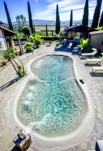 una piscina in un patio con sedie e alberi di villa porta a colle a Castiglione della Pescaia