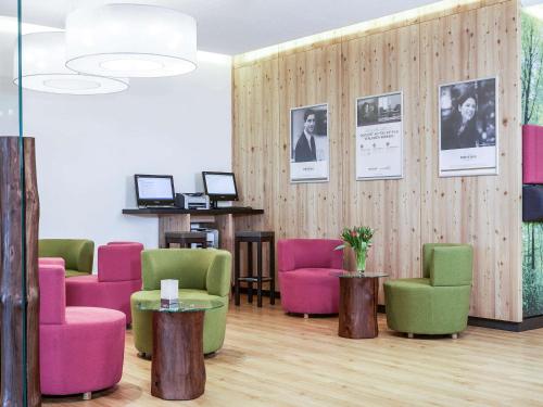 a waiting room with colorful chairs and pictures on the wall at Mercure Hotel am Messeplatz Offenburg in Offenburg