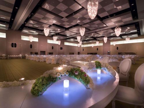 a banquet hall with white tables and chairs and chandeliers at Adagio Abu Dhabi Al Bustan in Abu Dhabi