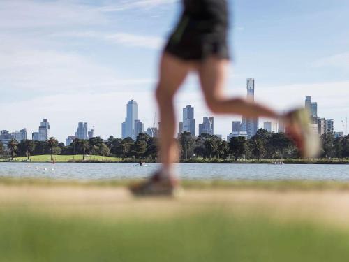 a woman is running in front of a city at Mercure Melbourne Albert Park in Melbourne