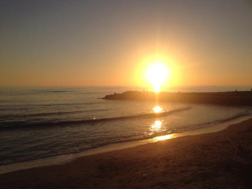 a sunset on the beach with the sun setting at Hotel La Scaletta in Lido di Ostia