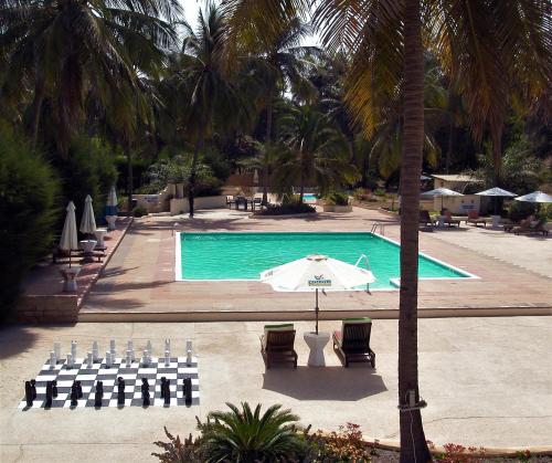 a pool with tables and chairs and an umbrella at Kololi Beach Resort in Kololi
