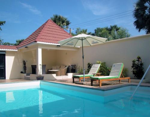 a swimming pool with two chairs and an umbrella at Kololi Beach Resort in Kololi