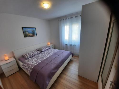 a bedroom with a bed with purple sheets and a window at Villa Antonio in Jelsa