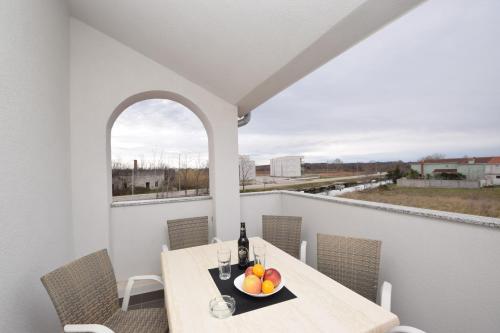 a table with a bowl of fruit on a balcony at Apartments Noa Nin Ždrijac in Nin